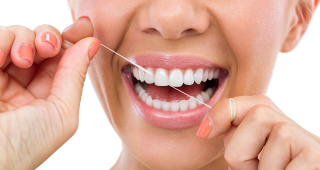 Eine Frau benutzt Zahnseide vor einer Zahnreinigung in Zürich-Enge Eine Frau benutzt Zahnseide vor einer Zahnreinigung in Zürich-Enge